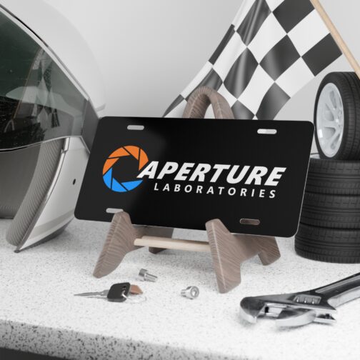 aperture-laboratories-decorative-vanity-license-plate-black-background-display-mockup Aperture Laboratories novelty license plate black background shown as a display piece, science laboratory vanity car tag. Inspired by Portal.