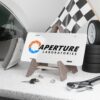 aperture-laboratories-decorative-vanity-license-plate-white-background-display-mockup Aperture Laboratories novelty license plate white background shown as a display piece, science laboratory vanity car tag. Inspired by Portal.