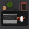 Aperture Laboratories orange logo black desk mat - overhead desk view with a laptop and mouse Black Portal desk mat with a large orange Aperture Laboratories logo, overhead desk view with a laptop and mouse